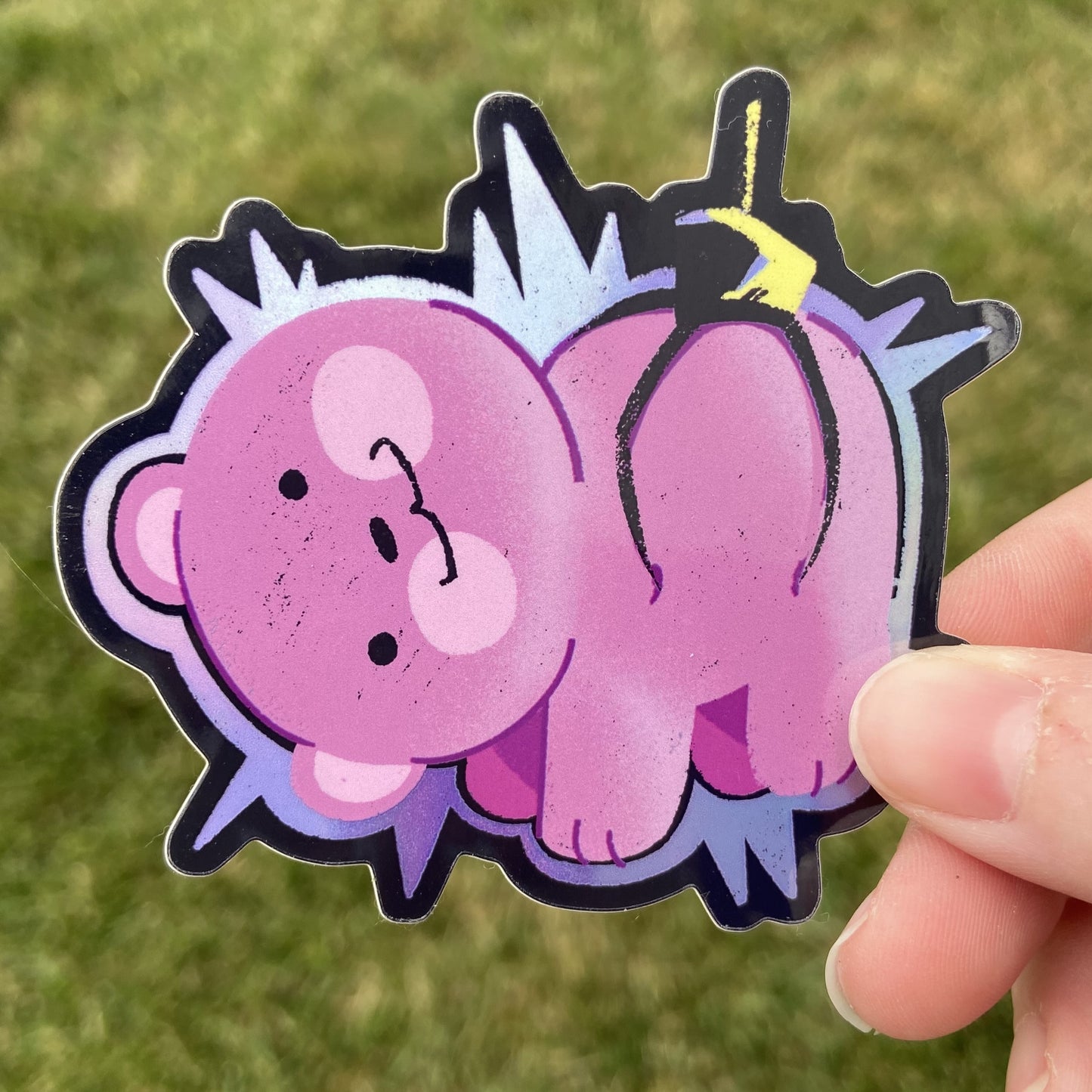 A vinyl sticker of a pink plush bear being lifted by a black crane game claw. The bear is surrounded with a holographic glow. The background is dark green.